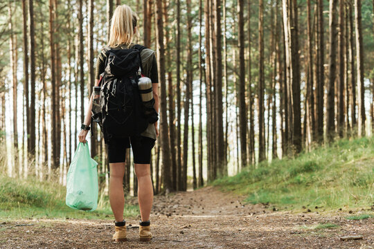 Female hiker collecting plastic waste in green forest