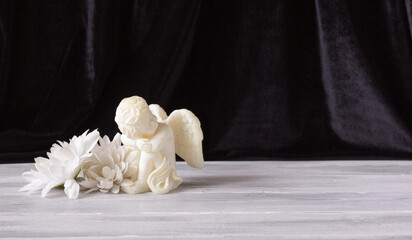 The concept of remembrance, funerals, and condolences. A small statuette of an angel with wings