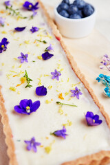 Fototapeta na wymiar cheesecake with blue flowers on a light background with berries close-up