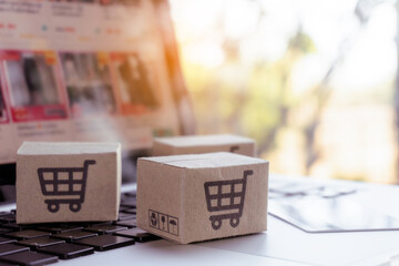 Online shopping. Credit card and cardboard box with a shopping cart logo on laptop keyboard. Shopping service on The online web. offers home delivery.