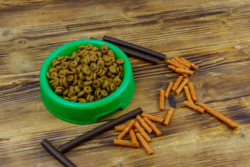 Dog delicacy food and feed in green plastic bowl on wooden background. Dog care concept