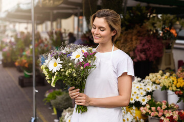 Fototapeta premium Woman florist with a bouquet of wildflowers in her little flower shop