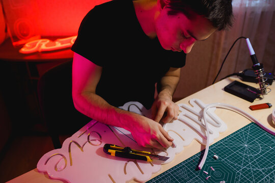 Man making signboard near stationery knife and soldering iron 