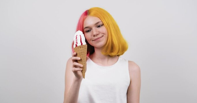 Smiling model teenager with ice cream in waffle cone over light gray studio background