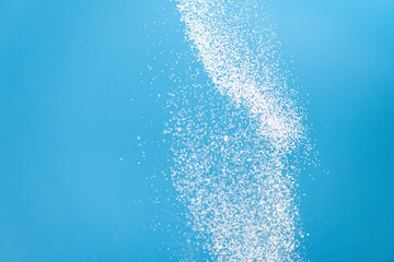 White powder splash isolated on blue background. Flour sifting on a blue background. Explosive...