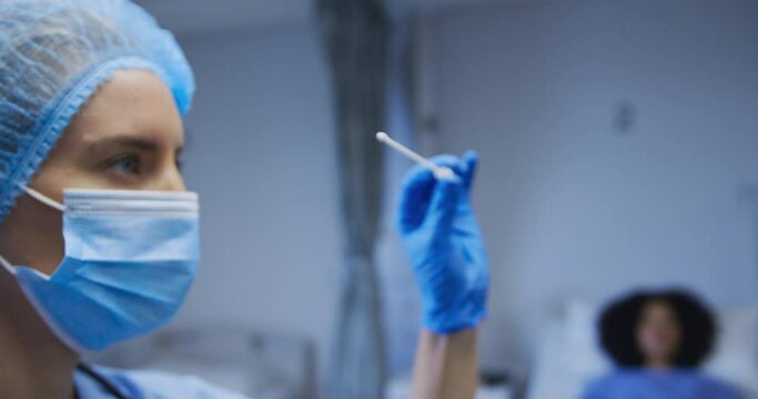 Female caucasian doctor wearing protective clothes reparing covid swab test for patient