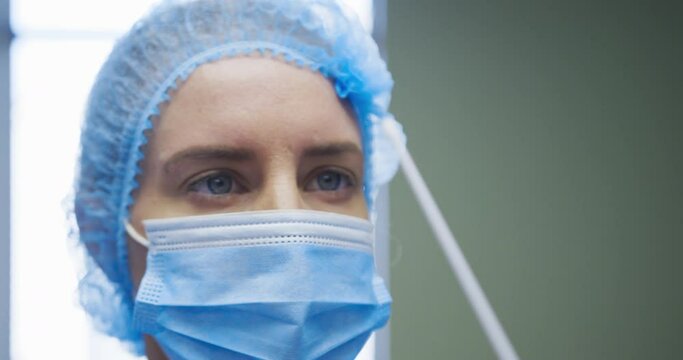 Female caucasian doctor wearing protective clothes reparing covid swab test for patient