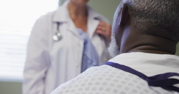 Mid section of female doctor talking and supporting african american senior male patient at hospital