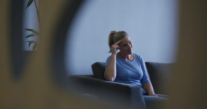 Tired caucasian woman sitting on sofa in hospital waiting room