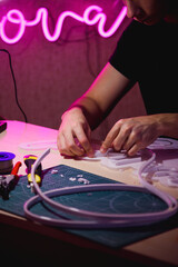 Craftsman making neon signboard with acrylic board near tools in workshop 