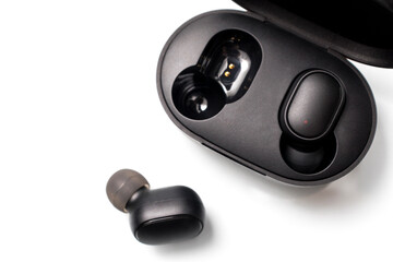 Black wireless bluetooth earphones or headphones, plastic case or box for storage and charging on...