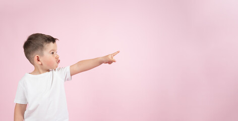 Funny boy pointing up to empty place on pink backgroun, banner for advertising product