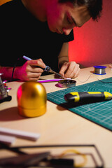 Craftsman using soldering iron on flex neon near tools while making signboard 