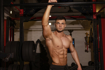 Fototapeta na wymiar Attractive tall muscular bodybuilder doing heavy deadlifts in modern fitness center.