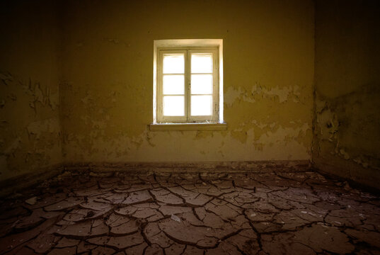 Room interior in abandoned house with cracked dirt on the floor and peeled paint on walls