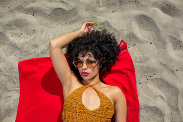 portrait of beautiful young mexican latin woman with sensual lips wearing sunglasses lying on the beach