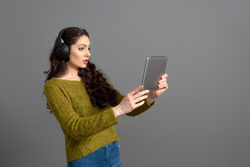 Naklejka premium young woman with headset and tablet in hand playing games and talking to friends online