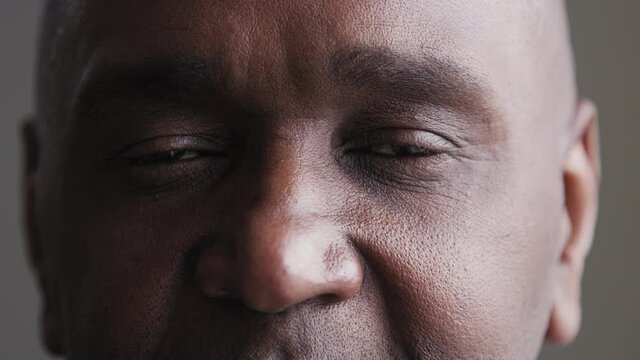 Close-up sad black male eyes looking at camera, african mature elderly man suffering from poor eyesight problem enjoying good vision after successful laser correction operation in ophthalmology clinic
