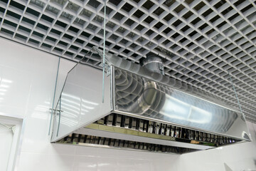 Suspended metal hood against a white wall. Kitchen equipment.