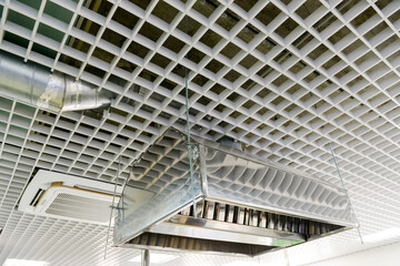 Suspended metal hood against the background of the lattice ceiling. Kitchen equipment.
