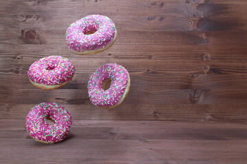Creative food concept: levitating dounuts on wooden background.