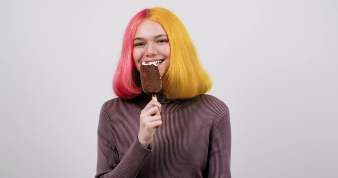 Young model teenager with chocolate ice cream in hand on light gray studio background