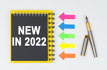 On a white background lies a pen, arrows and a notebook with the inscription - NEW IN 2022
