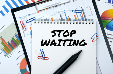 On the table are reports, charts, a notebook with the inscription - STOP WAITING