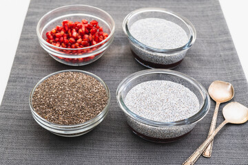 Chia seeds in a glass bowl, Chia seed pudding, and pomegranate seeds close up on kitchen table
