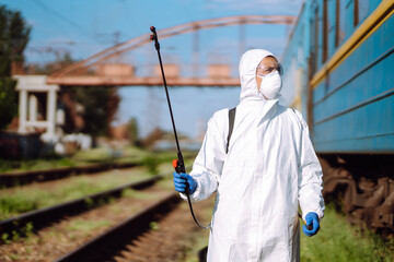 Man wearing protective suit disinfecting public a train with spray chemicals to preventing the spread of coronavirus, pandemic in quarantine city. Covid -19. Cleaning concept.