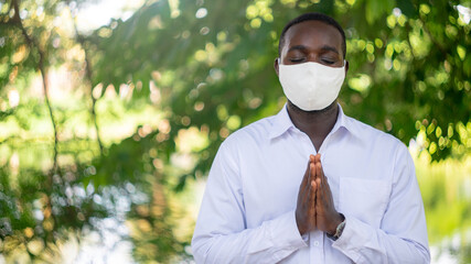 African Man Wearing Face Mask Praying in Faith against Corona virus or COVID-19.16:9 style