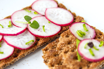 Bread rolls from crisped bread with chopped radishes and herbs. Sandwich with vegetables and basil. Snack close up.