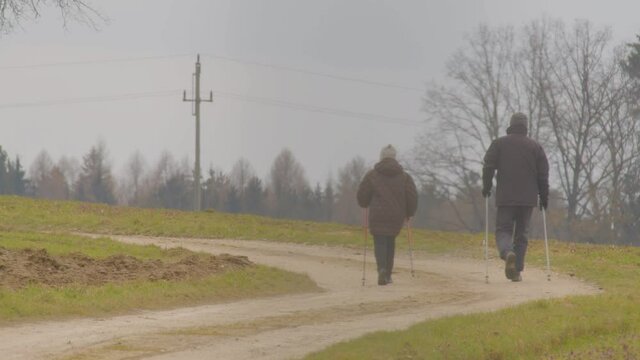 Older Couple Doing Nordic Walking In Countryside