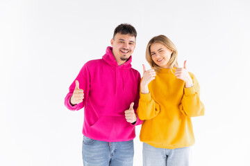 Portrait of excited enthusiastic couple promoters show thumb up recommend choice adverts hug wear color pullover good look isolated over white color background