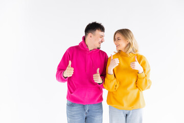 Portrait of excited enthusiastic couple promoters show thumb up recommend choice adverts hug wear color pullover good look isolated over white color background