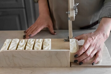 A woman makes handmade natural soap.The finished soap is cut into pieces using special machine....
