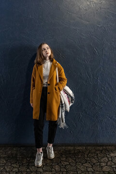 Portrait of a young teenager girl against a blue wall.
