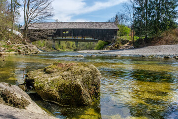 Alte gedeckte Holzbrücke über Fluss mit grünem Wasser