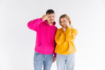 Portrait of a cheerful young couple wearing hoodies standing isolated over white background, ok gesture