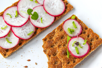 Bread rolls from crisped bread with chopped radishes and herbs. Sandwich with vegetables and basil. Snack close up.
