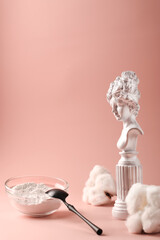 Health concept. Hydrolyzed collagen in a glass cup and black spoon on a pink background. Natural anti-aging supplement for beauty spa treatments. Vertical position. Copy space