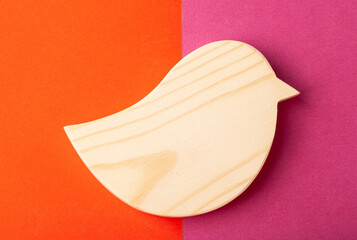 Figurine of a bird carved from solid pine by hand jigsaw. On a multi-colored background