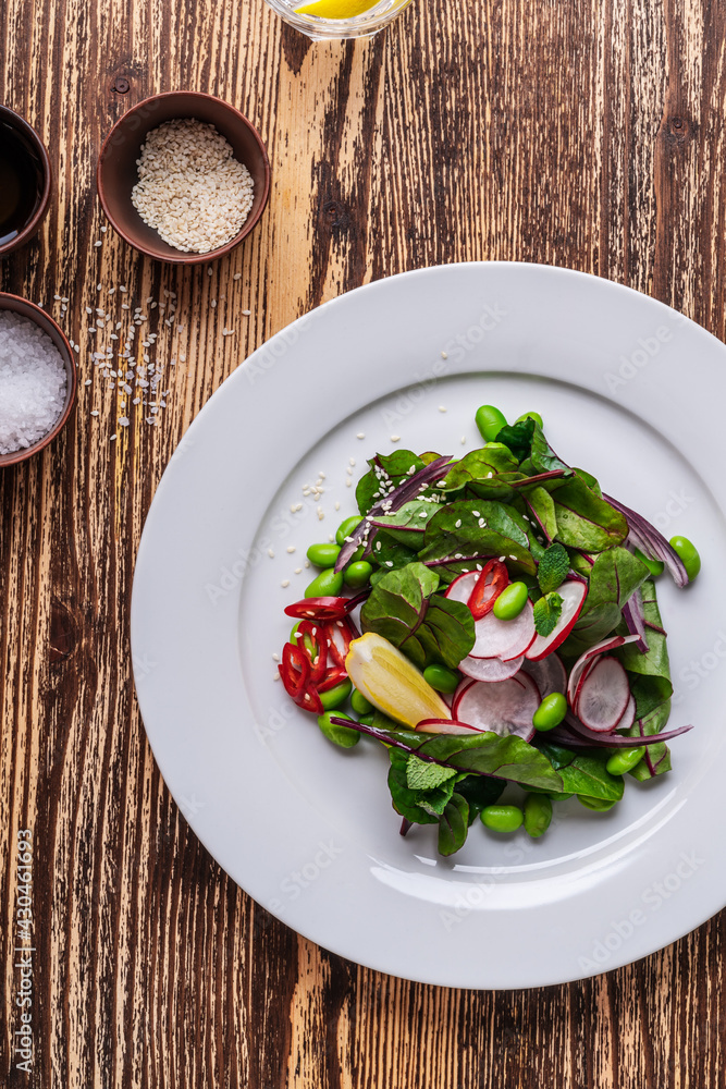 Poster Plate of fresh spring salad on rustic wood background. Chard leaves with radish