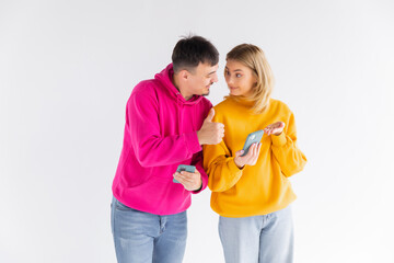 Photo of happy people man and woman laughing while pointing finger at smartphone isolated over white background