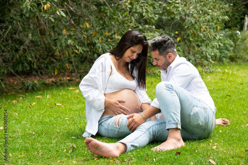 Couple of future parents sitting on the grass, pregnant woman. Maternity concept, mother's day.