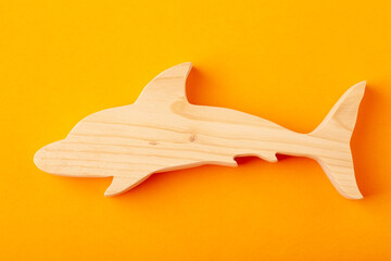 Dolphin figurine carved from solid pine by hand jigsaw. On a yellow background
