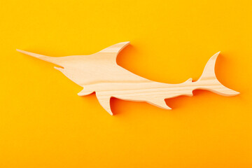 Figurine of a shark carved from solid pine by hand jigsaw. On a yellow background