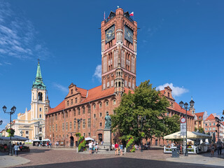Fototapeta na wymiar Torun, Poland. Old Town Market Square with Nicolaus Copernicus Monument in front of the Old Town Hall, and Church of the Holy Spirit in the background. The monument was erected in 1853.