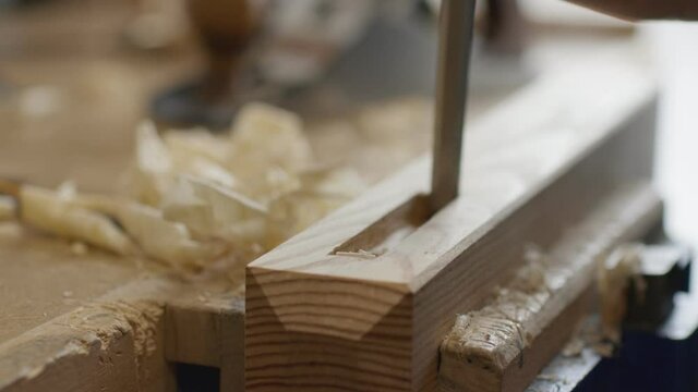 Carpenter carving wood using a chisel on his workbench. Woodworking and craftmanship concept