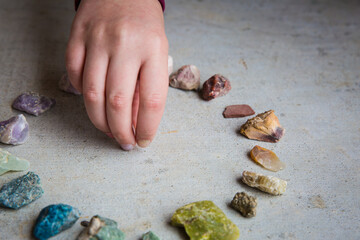 Child placing quartz in the middle of a circle of rocks and gems